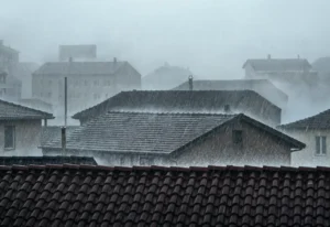 Intense hail and heavy rain splashing off tiled roofs causing hail damage.